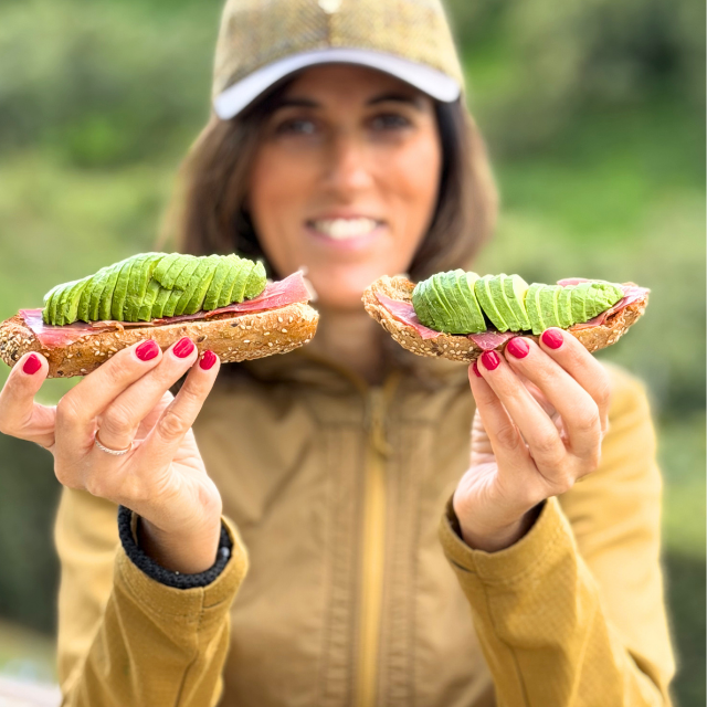 Woman holding two sandwiches with avocado and ham outdoors