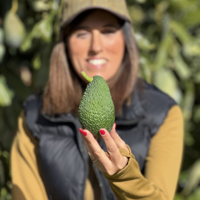 Kvinde med en økologisk Hass avocado på gården
